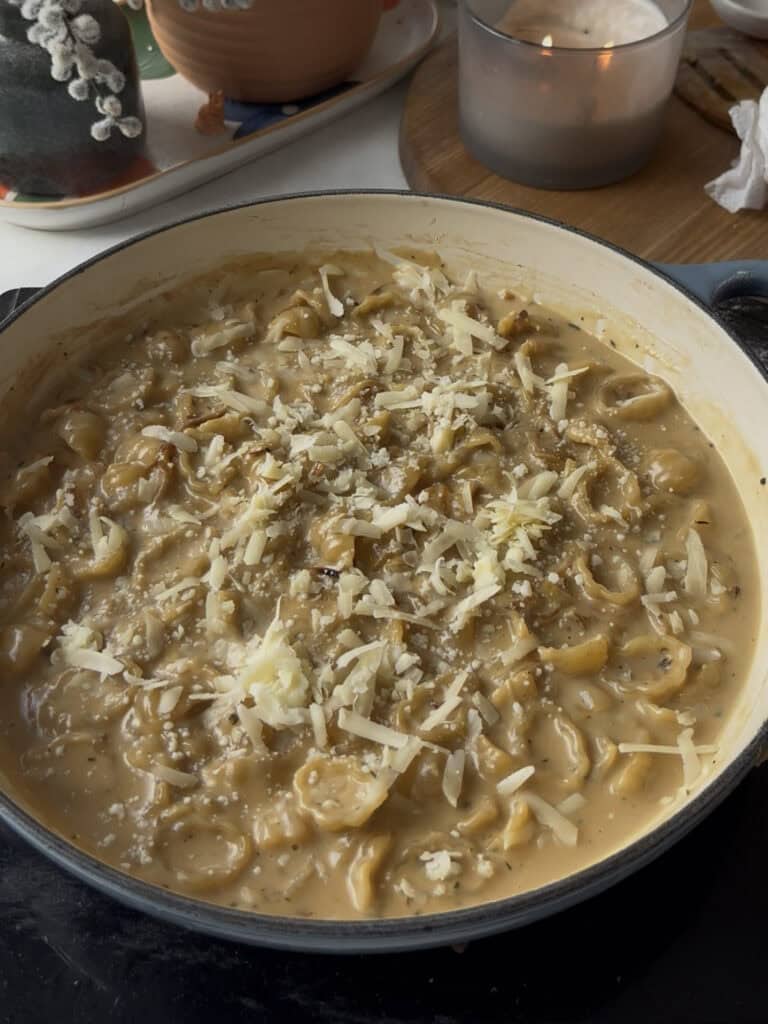 cheese sprinkled over the top of french onion pasta ready to be grilled