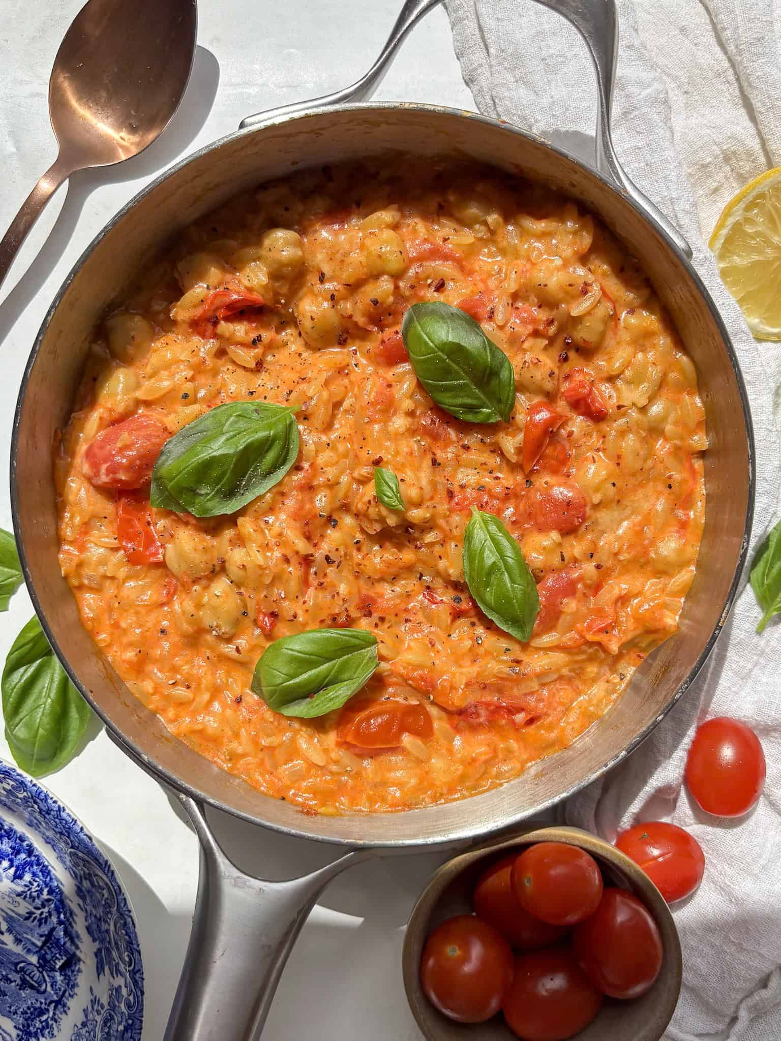 cherry tomato orzo topped with fresh basil in a skillet