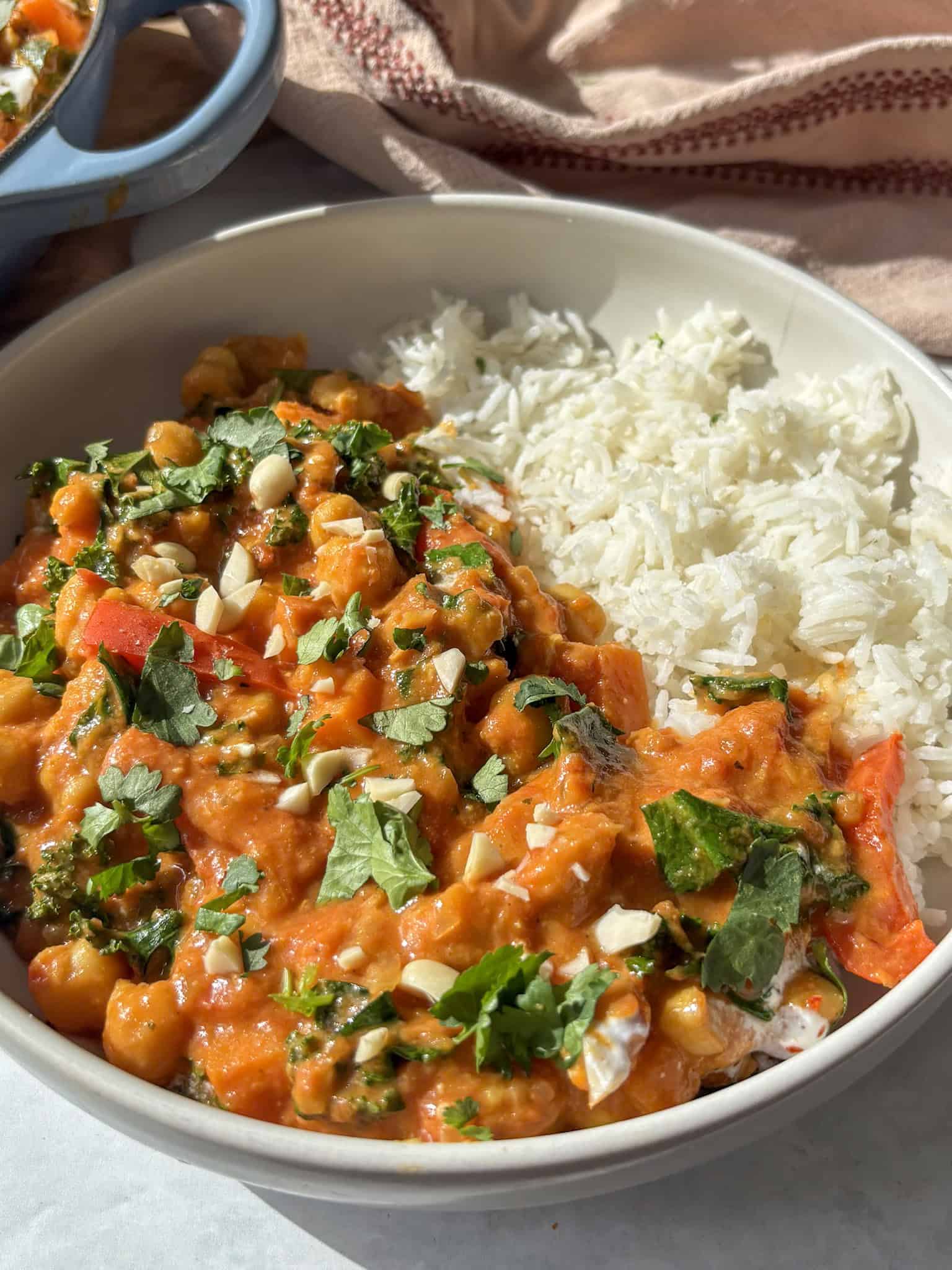 a bowl of peanut chickpea stew served with rice, topped with chopped peanuts and fresh coriander