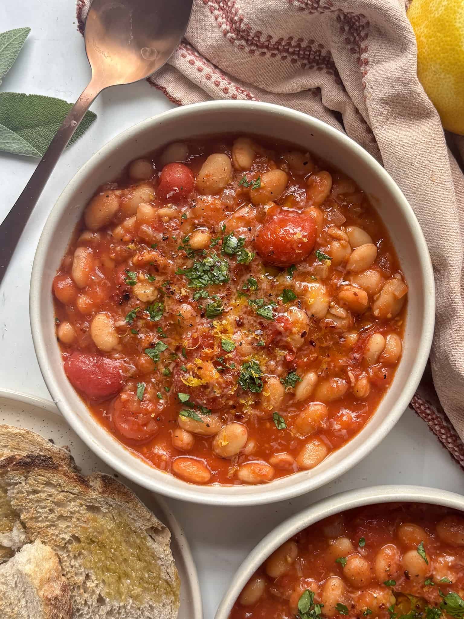 white bean stew with cherry tomatoes and a topping of fresh herbs, lemon zest, and red pepper flakes.